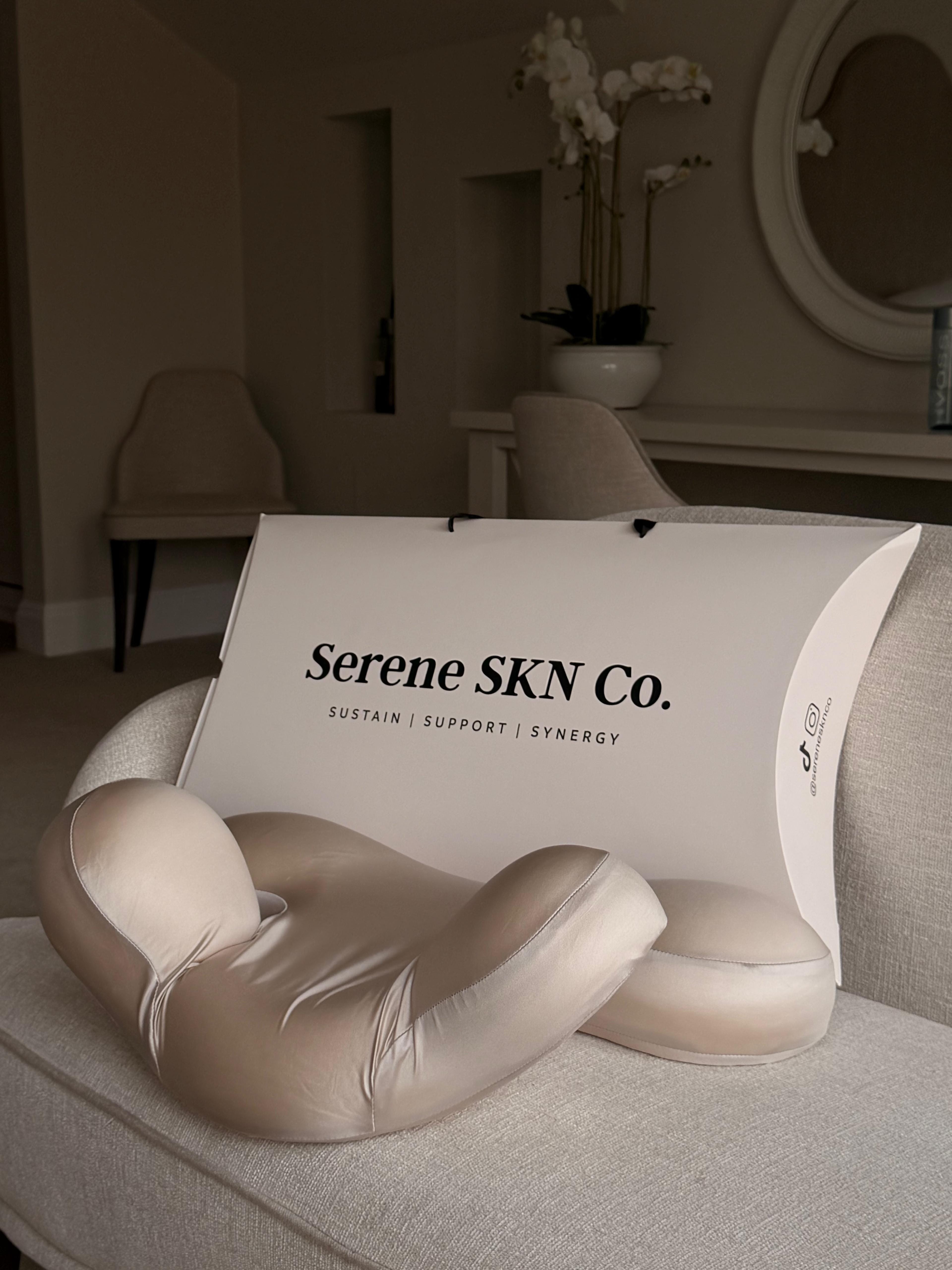 Beige neck pillow on a couch with 'Serene SKN Co.' branding in a home setting.