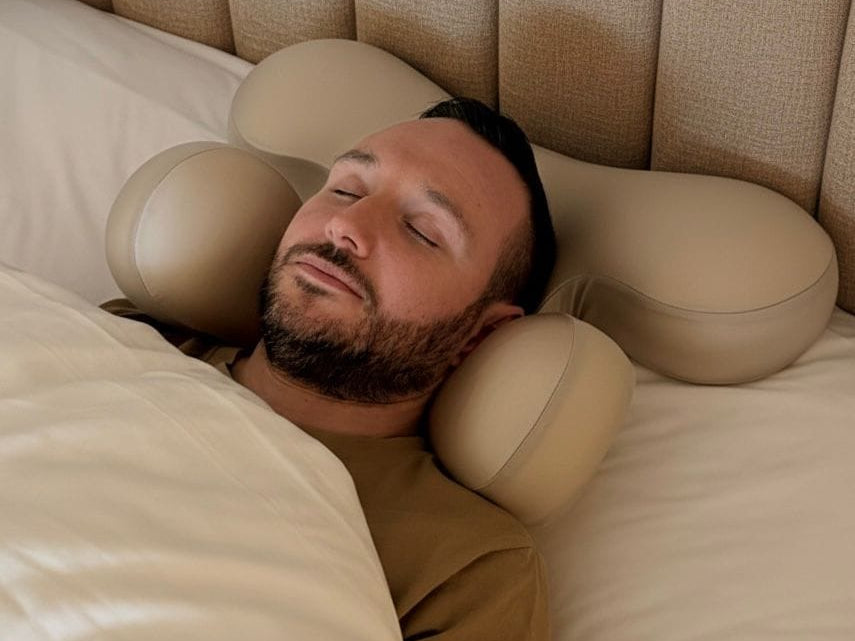Man sleeping on Serene SKN Co anti-wrinkle ergonomic sleep pillow in beige, back sleeping position in a luxury bedroom setting